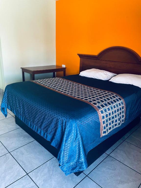a bed in a room with an orange wall at Belmont Motel in Roswell