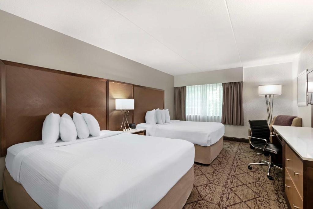 a hotel room with two beds and a desk at Best Western Plus Longbranch Hotel & Convention Center in Cedar Rapids