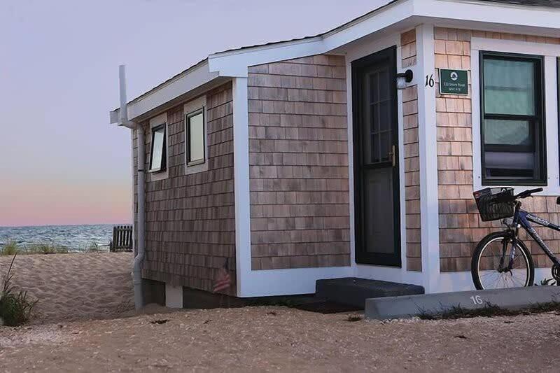 a house on the beach with a bike parked next to it at Peaceful Waterfront Beach Cottage! in Truro