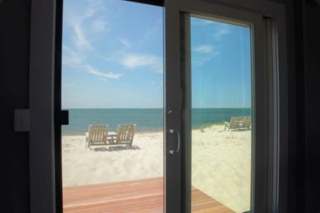a sliding glass door with a view of the beach at Cozy Beach Bungalow in Truro