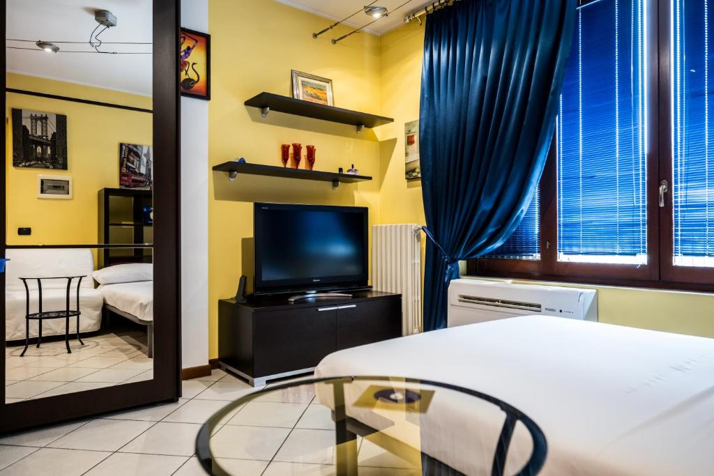 a room with a bed and a tv and a mirror at Cozy Suite Rogoredo Apartment next to the metro and train station in Milan