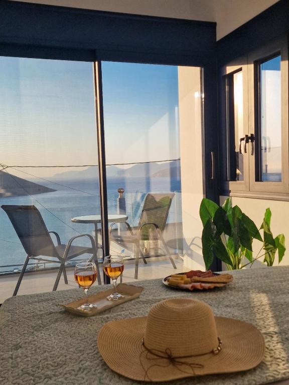 a table with a hat and two glasses of wine at Regina - Luxury Apartments in Kalymnos