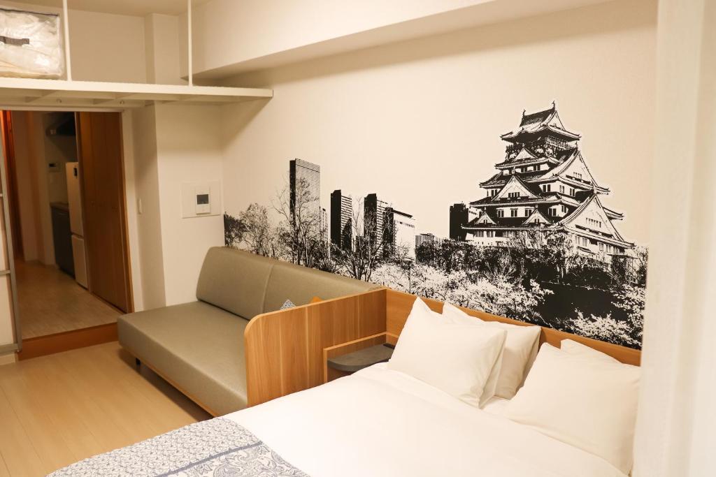 a room with a bed and a couch and a wall mural at yksi STAY ＆ APARTMENT OSAKA in Osaka