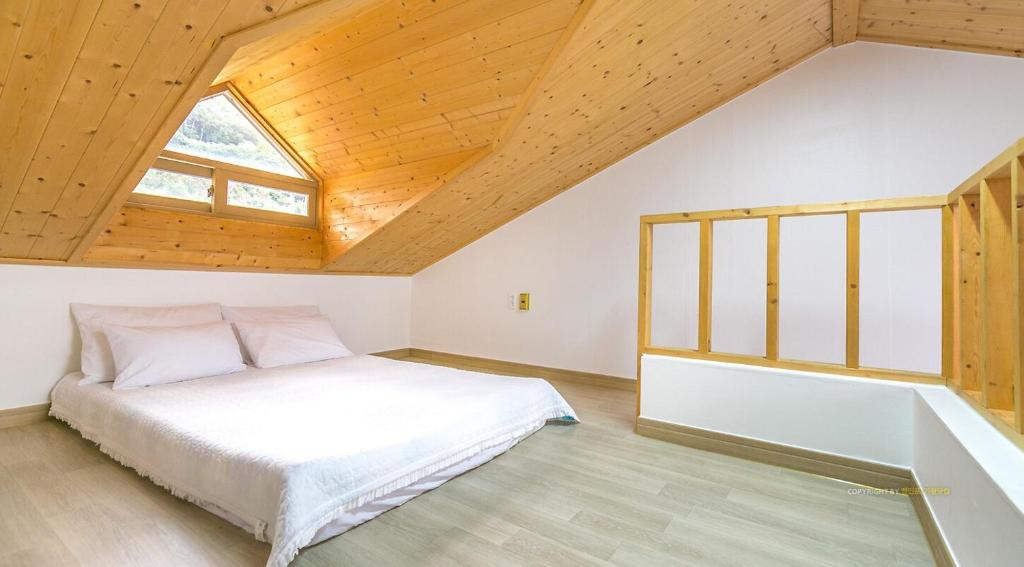 ein Schlafzimmer mit einem Bett auf einem Dachboden in der Unterkunft Geojae Beach Maru Pension in Geoje