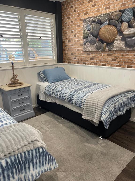 a bedroom with a bed and a brick wall at Private, modern 2 bedroom apartment Thornlands in Thornlands