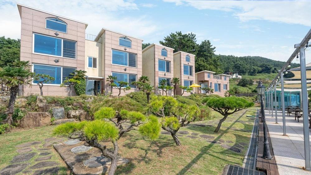 an apartment building with trees in front of a street at Namhae Healing Time Pension in Namhae