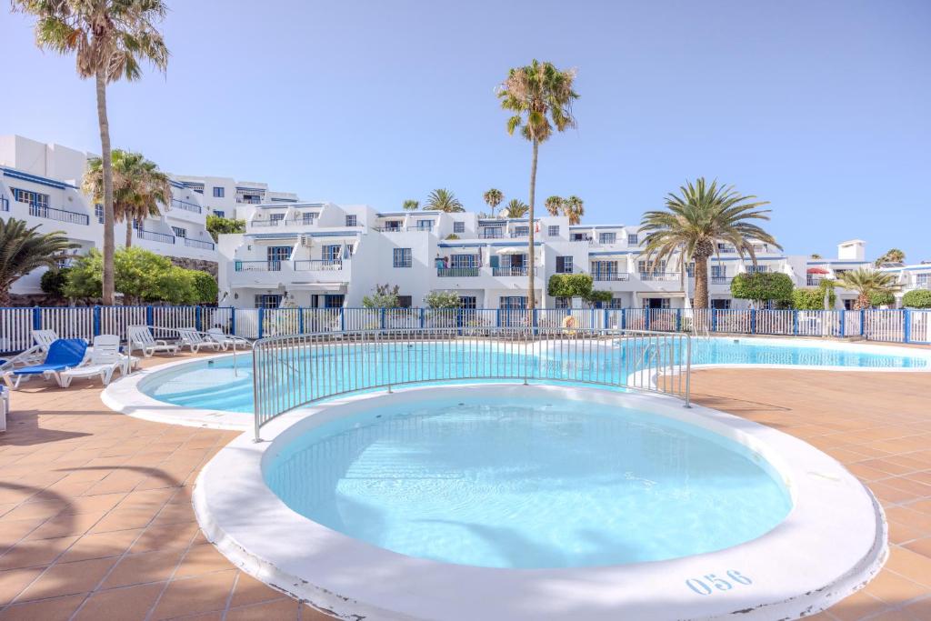 a large swimming pool with palm trees and a building at Atalaya 2 Sea View - Puerto del Carmen in Tías