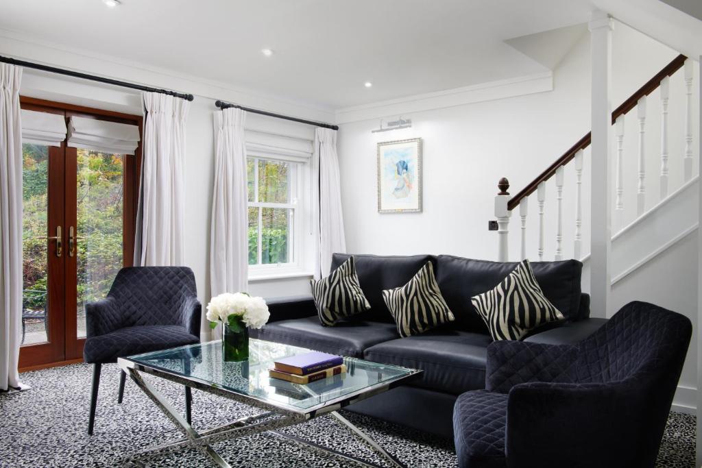 a living room with a black couch and two chairs at The Lodge at Ashford Castle in Cong