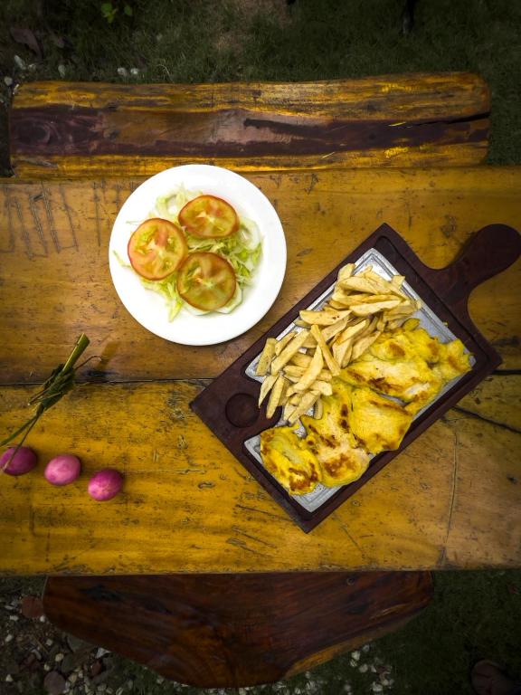 a table with a plate of food and a plate of fries at Los Achiotes Hostal - Palomino in Palomino