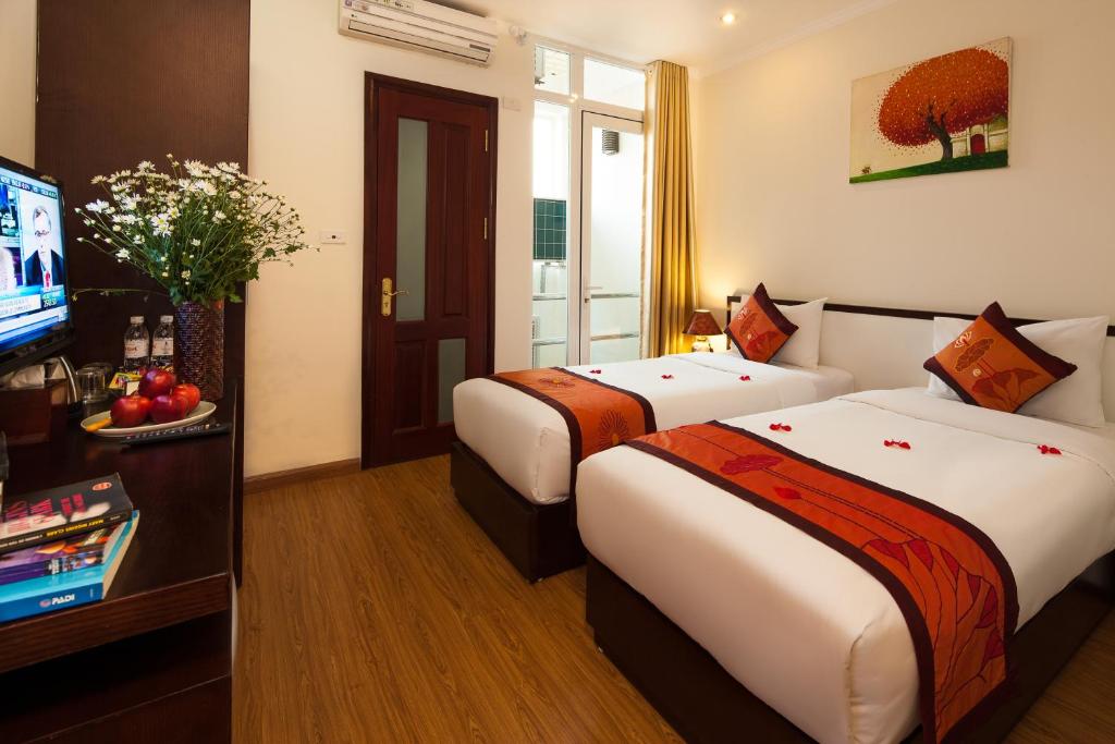 a hotel room with two beds and a television at Rising Dragon Hotel in Hanoi