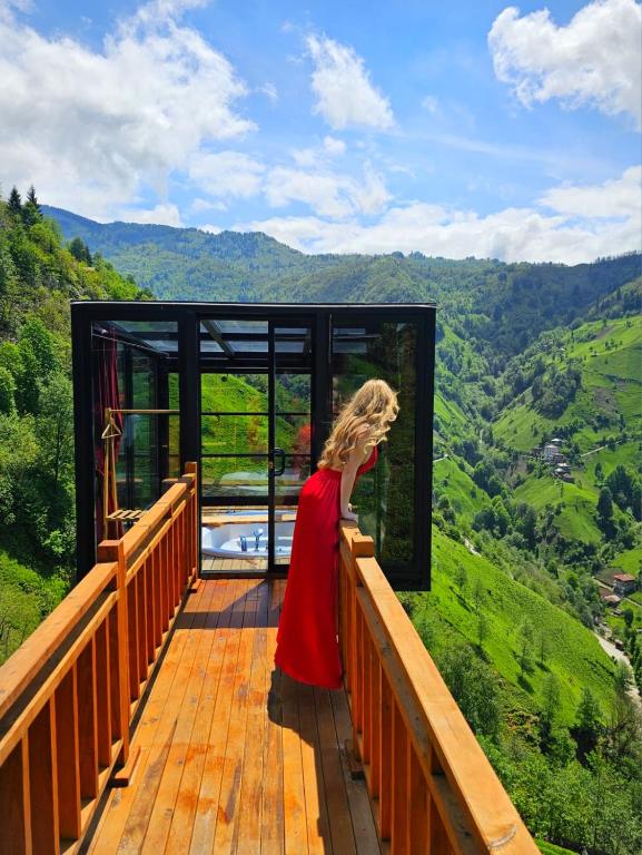 a woman in a red dress standing on a wooden deck at Northland Bungalows in Çayırdüzü