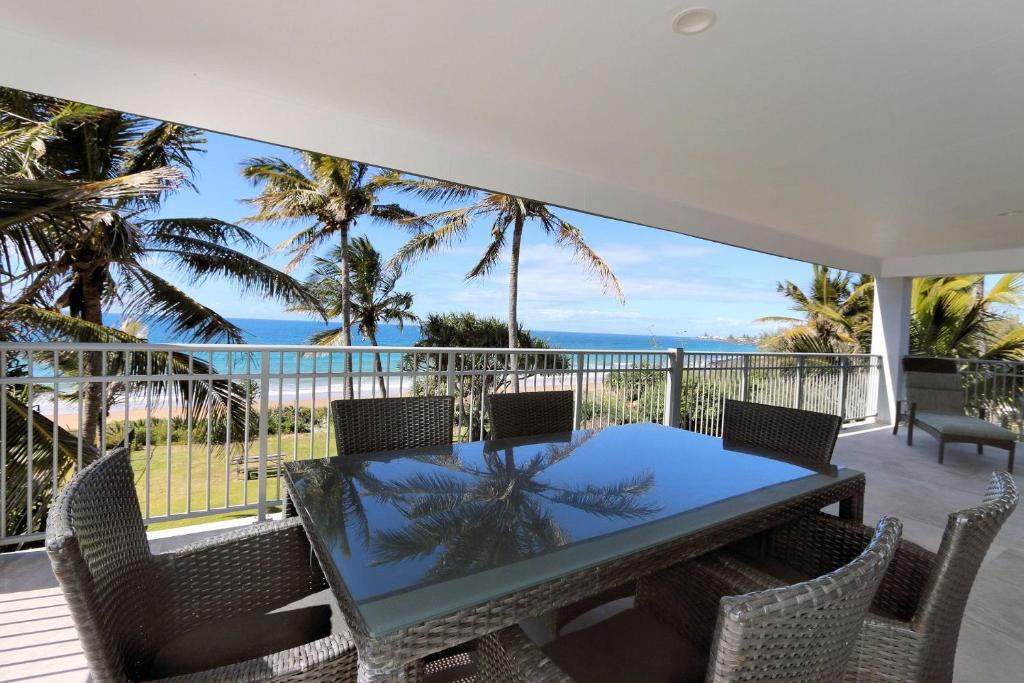 a dining table and chairs on a balcony with the ocean at Horizons Unit 4 Beachfront Unit in Bargara