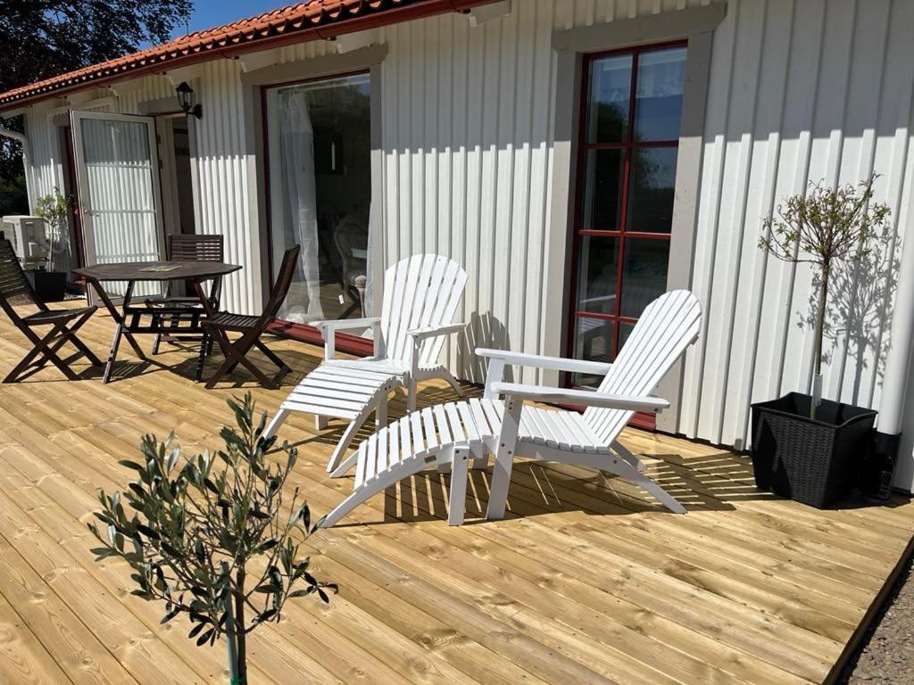 three white chairs and a table on a wooden deck at Brittas Country House in Munka-Ljungby