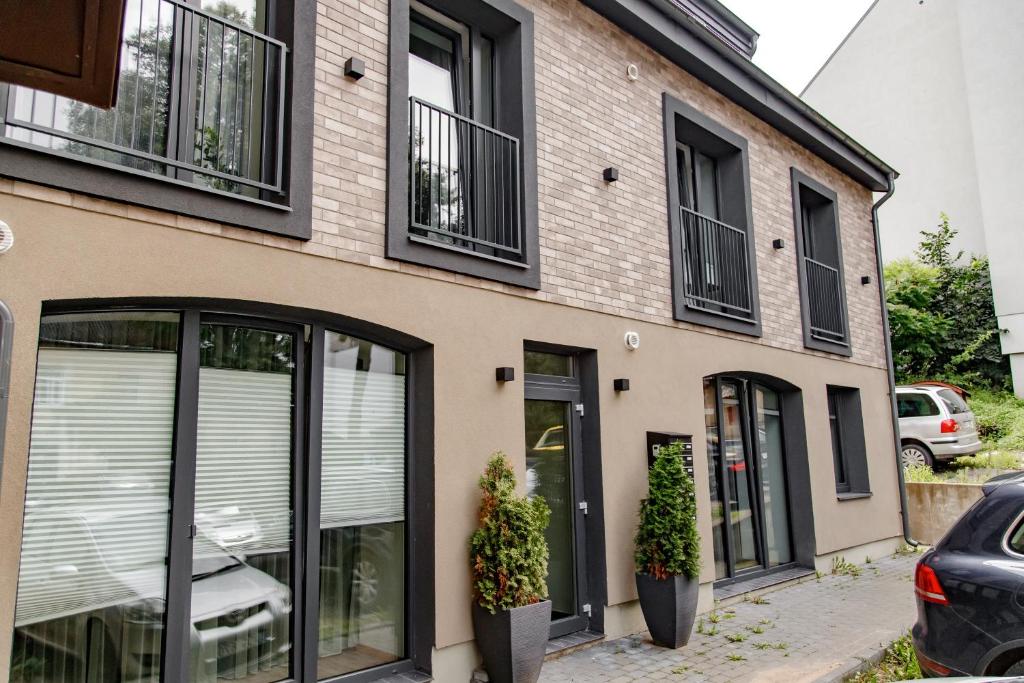 a building with black windows and plants on the sidewalk at Hales Old Town Urban Apartments in Vilnius