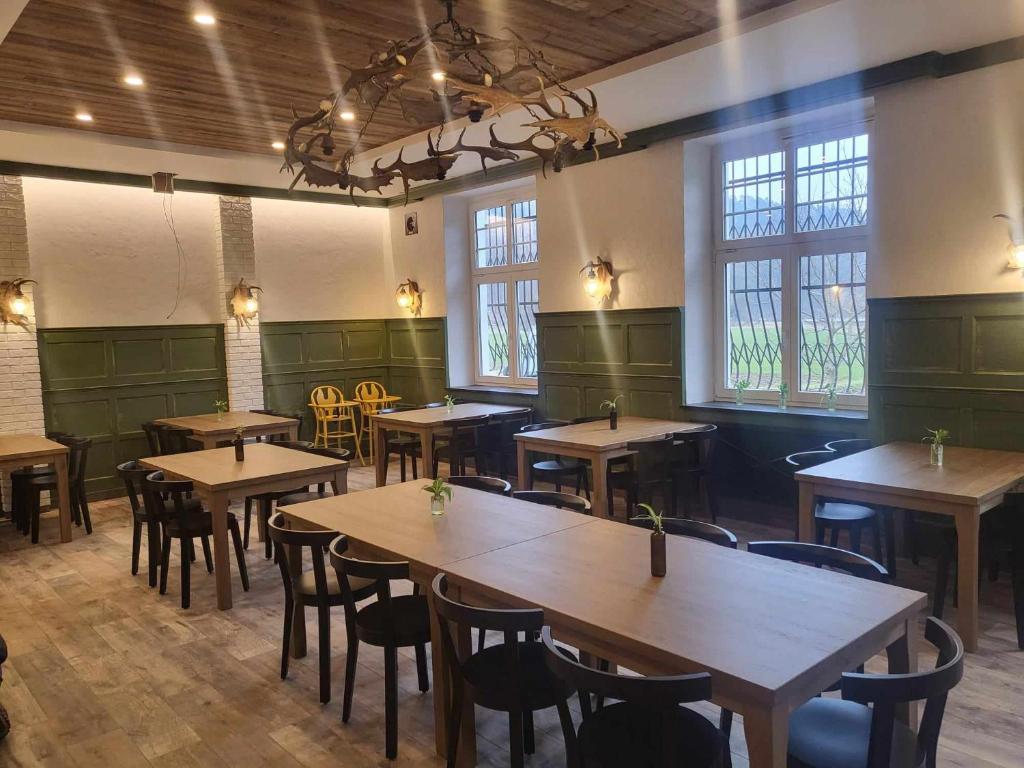 restauracja z drewnianymi stołami i krzesłami oraz oknami w obiekcie Penzion a Restaurace Bělecký Mlýn w mieście Ptení