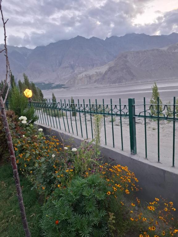 a fence next to a field of flowers at Hotel Blangsa Indus View in Skardu