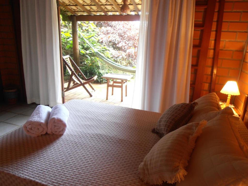 a bedroom with a bed with towels and a window at Pousada Rosa & Canela in Praia do Rosa