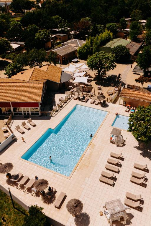 une vue aérienne d'une piscine avec chaises et parasols dans l'établissement Slow Village Marennes Oléron, à Marennes