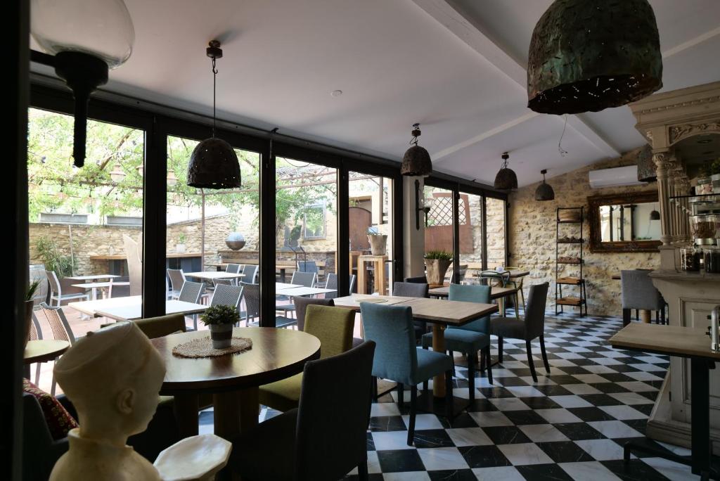 un ristorante con tavoli, sedie e finestre di Chambres du Vieux Bistrot a Cabrières-dʼAvignon