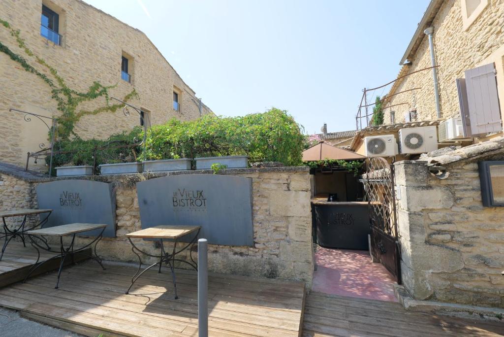 un patio con tavolo e sedie accanto a un edificio di Chambres du Vieux Bistrot a Cabrières-dʼAvignon