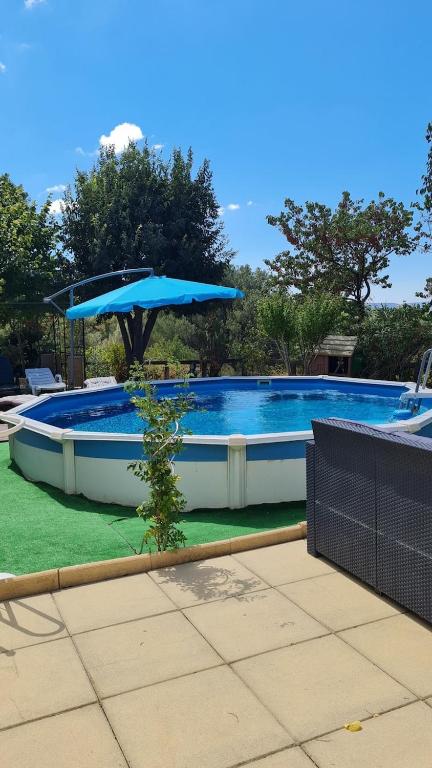 une grande piscine avec un grand parasol bleu dans l'établissement Maison Familiale Rdc Roquevaire, à Roquevaire