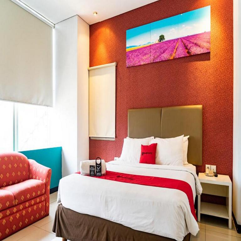 a bedroom with a large bed and a red wall at RedDoorz Plus at Blue Pacific Blok M in Jakarta