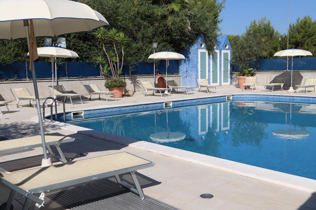 a swimming pool with chairs and umbrellas at Residence Ada in Grottammare
