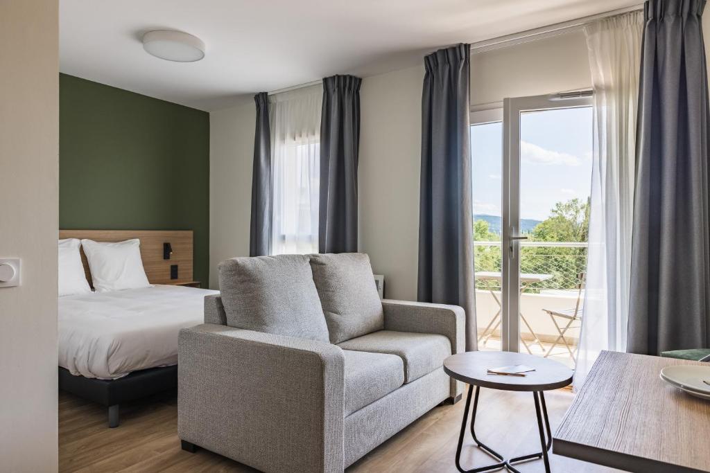 una camera da letto con un letto, un divano e una sedia di Hôtel des Thermes des Fumades ad Allegre Les Fumades