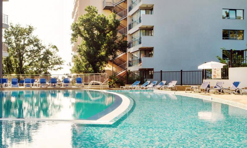 a large swimming pool with chairs and a building at Arena Mar Hotel and SPA in Golden Sands