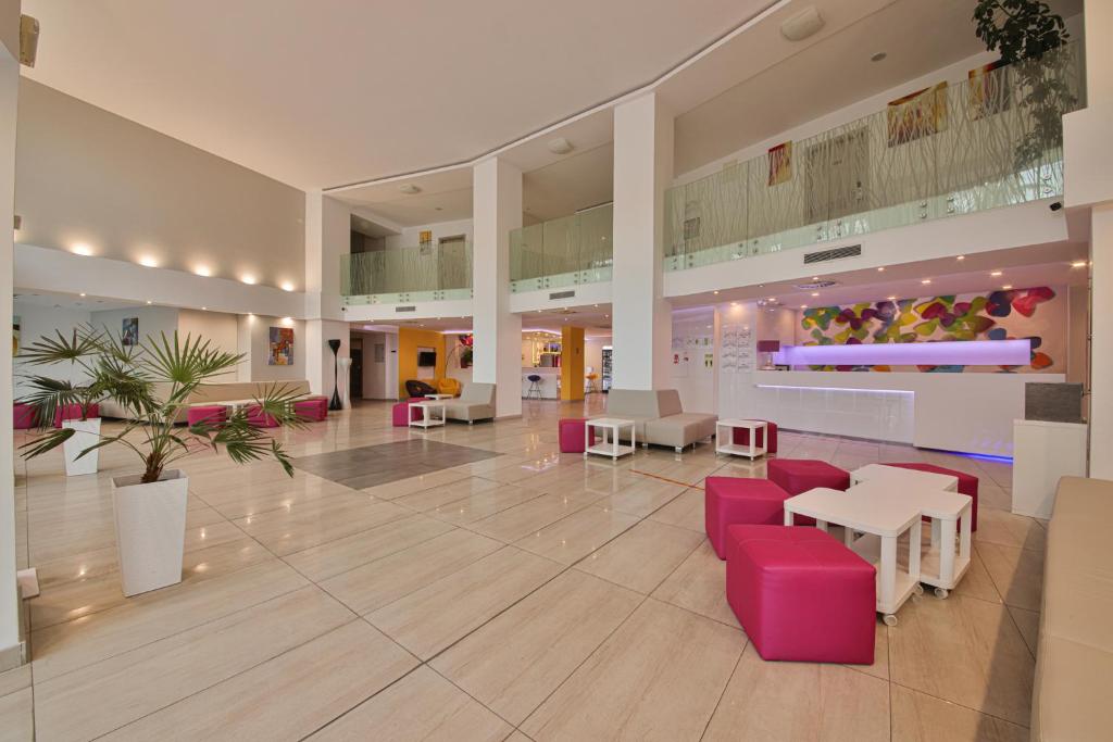 a lobby with pink chairs and tables in a building at Arena Mar Hotel and SPA in Golden Sands