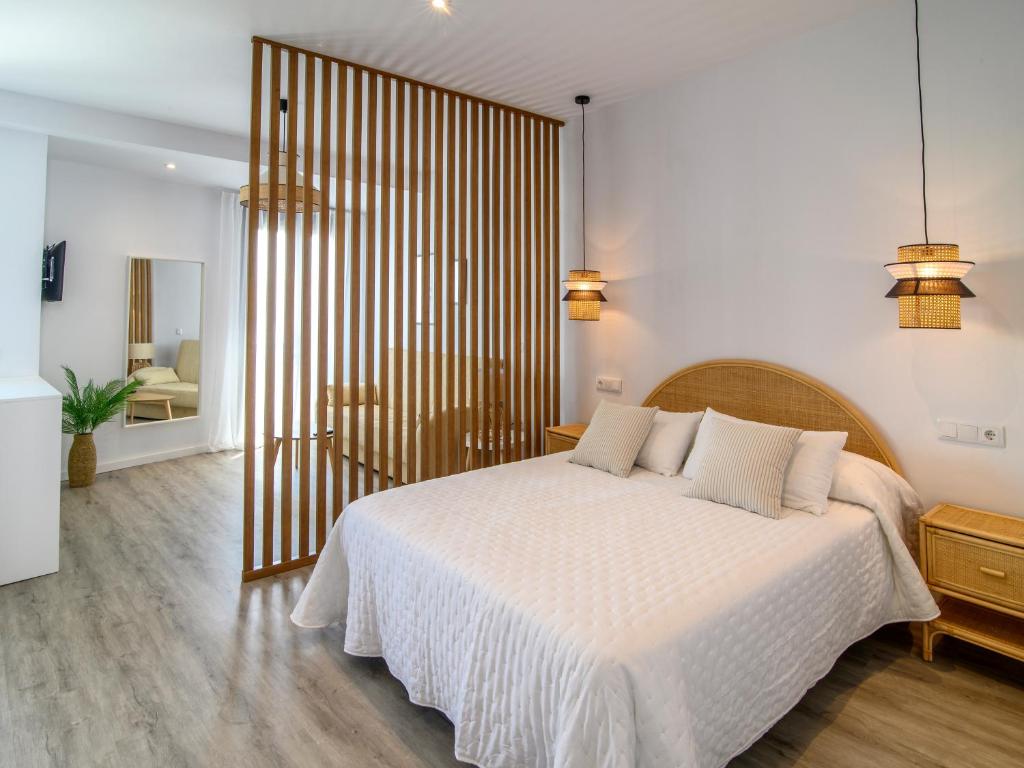 een slaapkamer met een groot bed met witte lakens bij Antonella Suites in Fuentes de Andalucía