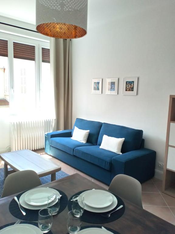 un salon avec un canapé bleu et une table dans l'établissement Le Petit Appart au coeur de Vichy, à Vichy
