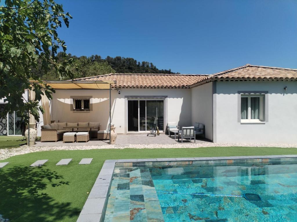 a villa with a swimming pool in front of a house at Jolie villa au calme avec piscine in Méounes-lès-Montrieux
