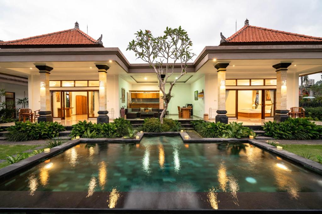a villa with a swimming pool in front of a house at Griya Private Villa in Ubud