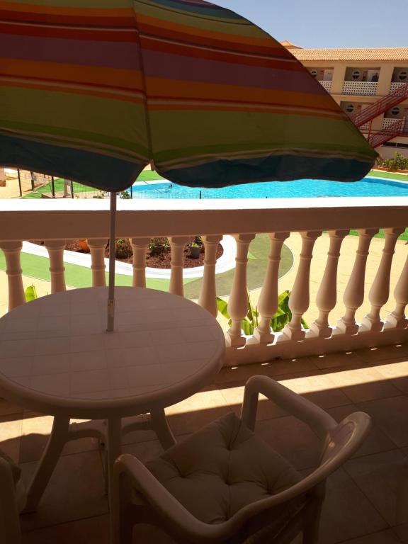 a table and a chair on a balcony with an umbrella at Chill Out Tenerife Sud - monolocale con piscina riscaldata in Costa Del Silencio