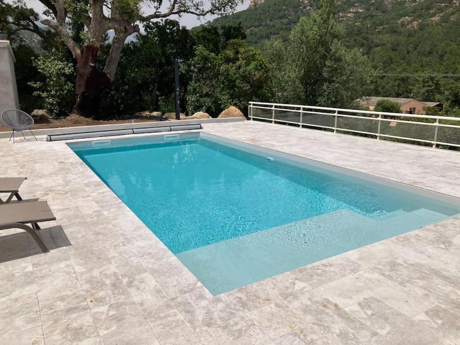 une piscine avec de l'eau bleue dans une cour arrière dans l'établissement A SUARELLA - Villa climatisée - 4 chambres - piscine chauffée, à Sainte-Lucie de Porto-Vecchio