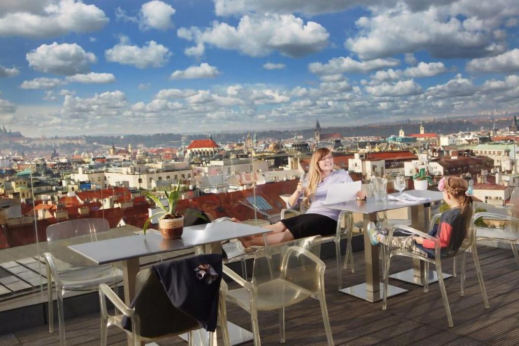 a woman sitting at a table on a roof at Wenceslas Square Hotel - Czech Leading Hotels in Prague