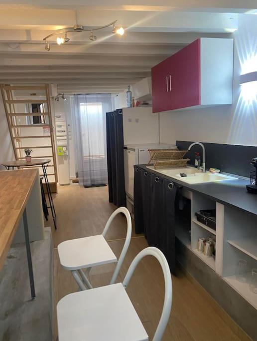 une cuisine avec des chaises blanches, un comptoir et des armoires dans l'établissement Appartement 60m2 - 2 ou 4 pers, à Biziat
