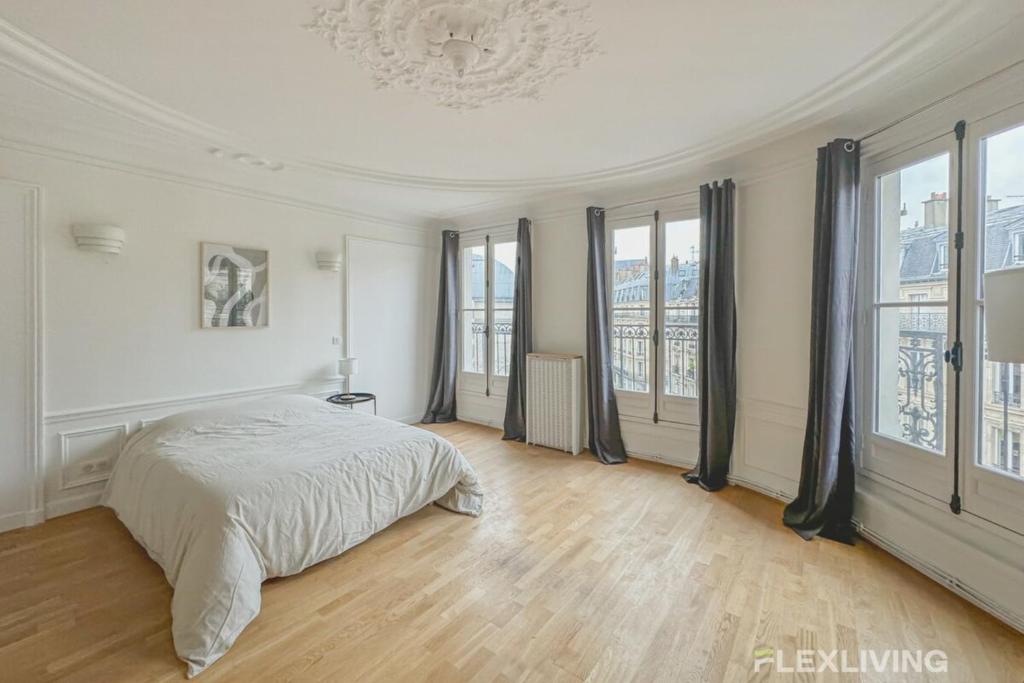- une chambre blanche avec un lit et de grandes fenêtres dans l'établissement Flexliving - room - Turbigo, à Paris