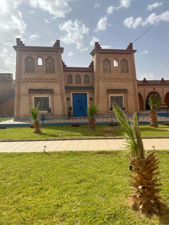 ein Gebäude mit einer Palme davor in der Unterkunft Kasbah des merveilles Dades in El Hart