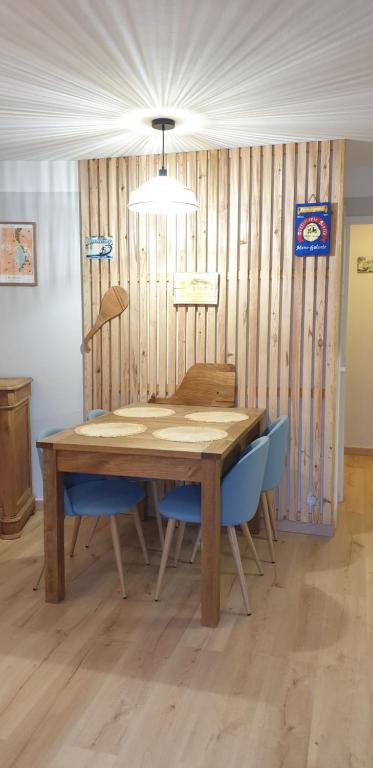 - une table en bois avec des chaises bleues dans l'établissement Bienvenue à l'Appart' !, à Lacanau