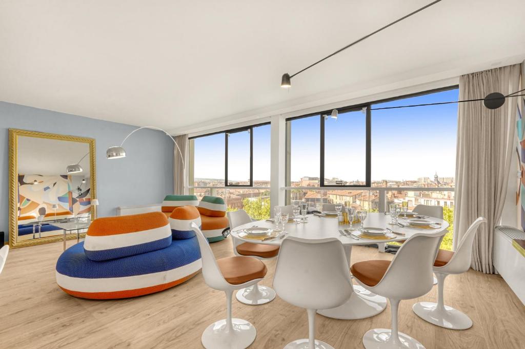une salle à manger avec une table, des chaises et des fenêtres dans l'établissement L’échappée Capitulaire - Belle vue de Toulouse, à Toulouse