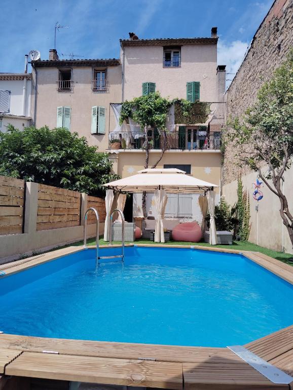 une grande piscine bleue avec un parasol dans l'établissement Maison chez Marthe, au Muy