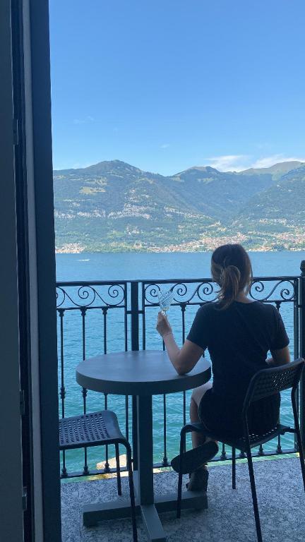 a woman sitting at a table on a balcony at Lake Mirror in Lezzeno