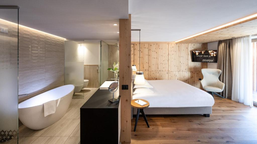 a bedroom with a tub and a bed and a bath tub at Ciampedie Luxury Alpine Spa Hotel in Vigo di Fassa