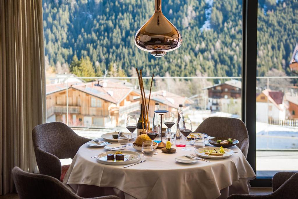 a table with plates of food and a large window at Ciampedie Luxury Alpine Spa Hotel in Vigo di Fassa