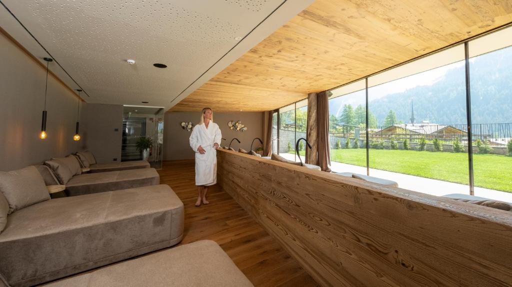 a woman standing in a room with a large window at Ciampedie Luxury Alpine Spa Hotel in Vigo di Fassa