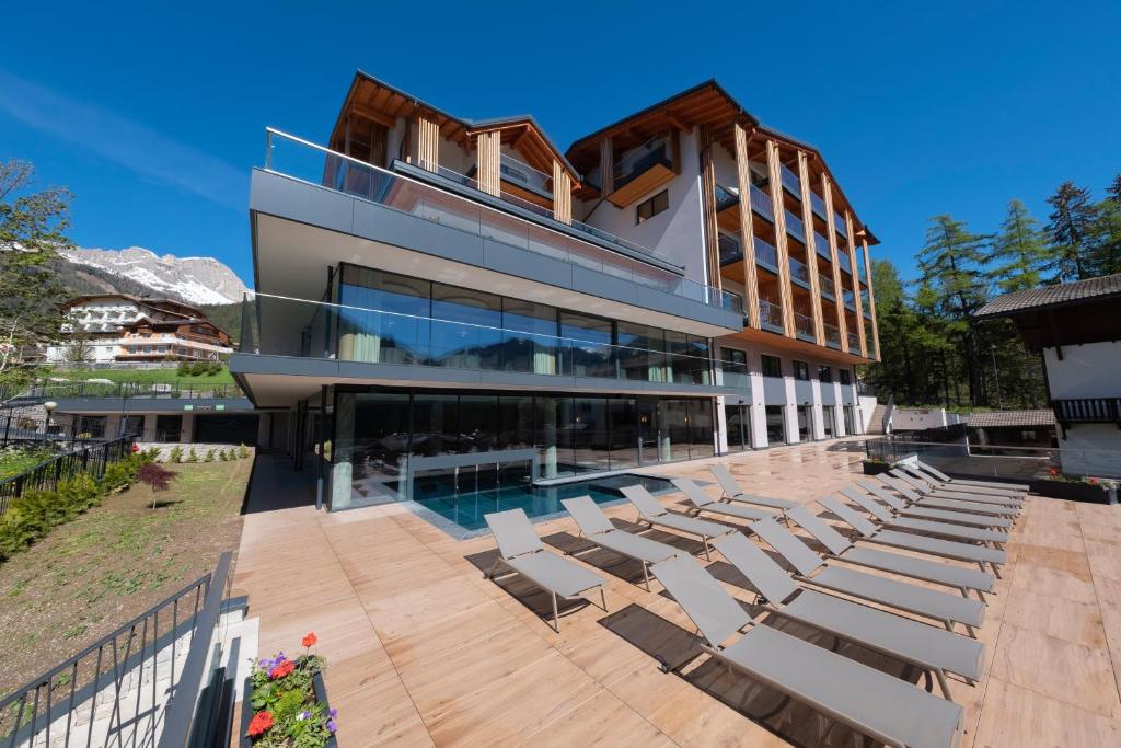 a house with a swimming pool and lounge chairs at Ciampedie Luxury Alpine Spa Hotel in Vigo di Fassa