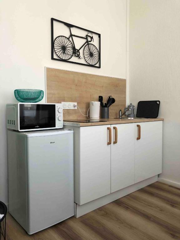 une cuisine équipée d'un four micro-ondes sur un comptoir avec un vélo sur le mur dans l'établissement Le Doux Refuge, à Calais