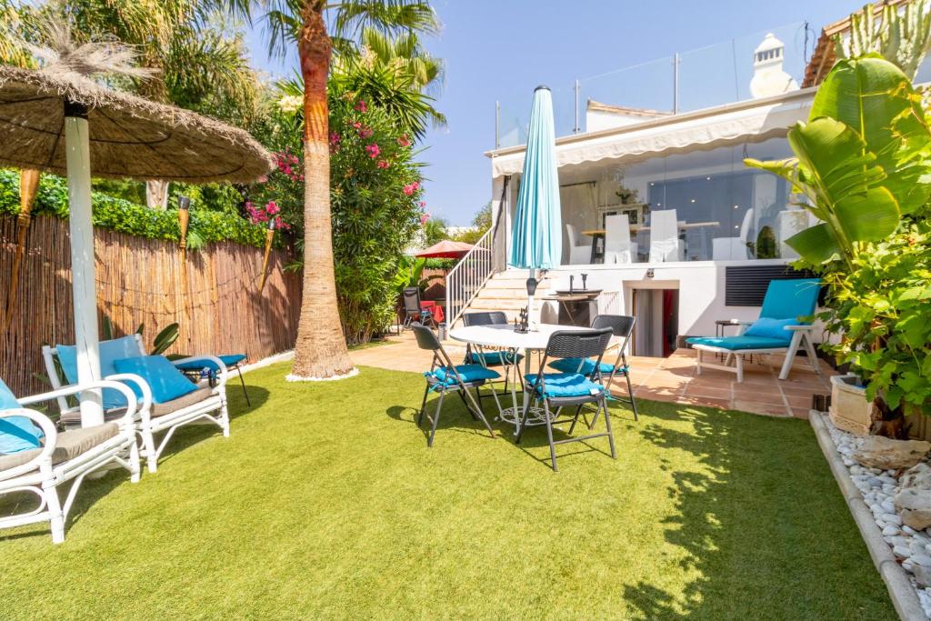 a yard with chairs and a table and umbrella at Villa Bahia Dorada in Estepona